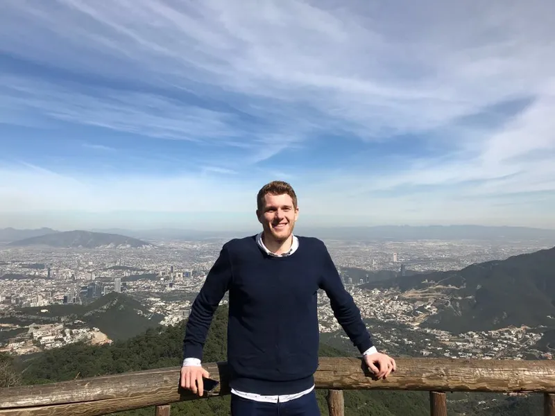 Niklas smiling at a lookout above a big city and mountains