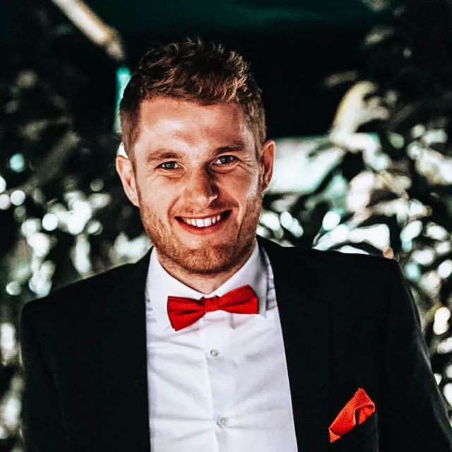 Niklas Coors in a dark suit with a red bow tie, smiling