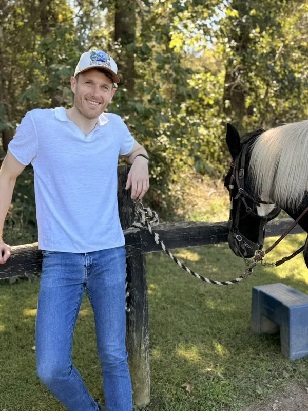 Niklas leaning on a wooden fence next to a horse